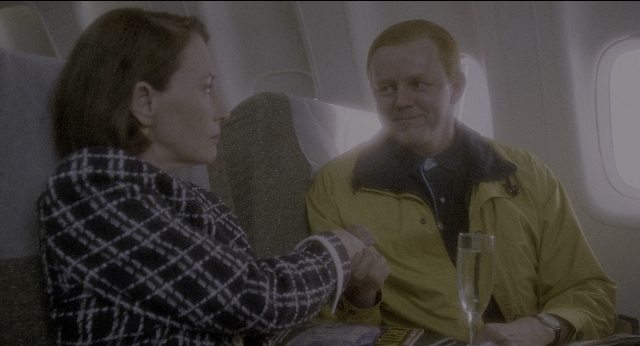 Wide shot frame from Twelve Monkeys — sitting, dialogue, hand