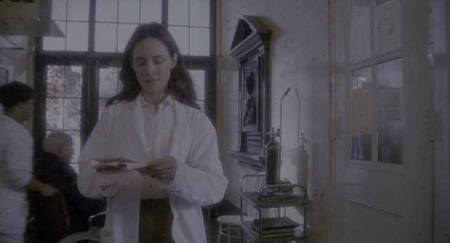 Wide shot frame from Twelve Monkeys — standing, room, door