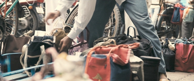 Wide shot frame from The Lunchbox — walking, street, hand