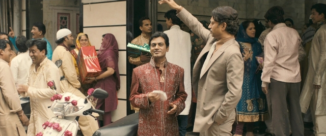 Medium shot frame from The Lunchbox — standing, street, suit