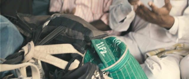 Wide shot frame from The Lunchbox — sitting, shirt, backpack