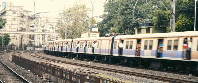 Wide shot frame from The Lunchbox — standing, train, person