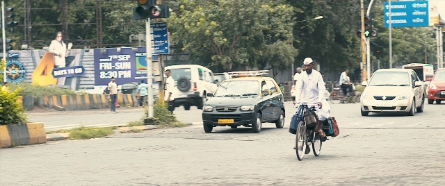 Wide shot frame from The Lunchbox — walking, street, hat