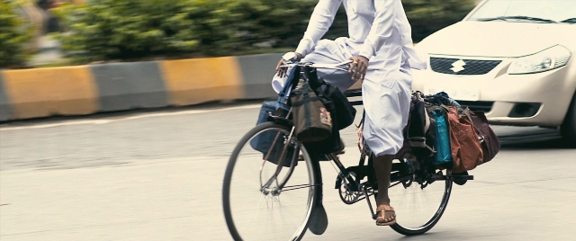 Wide shot frame from The Lunchbox — street, car, bicycle