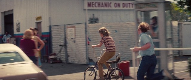 Wide shot frame from Licorice Pizza — standing, walking, dialogue