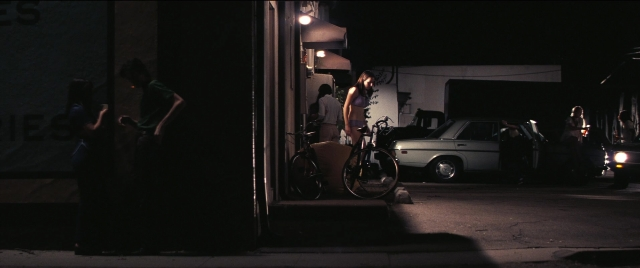 Wide shot frame from Licorice Pizza — standing, street, car