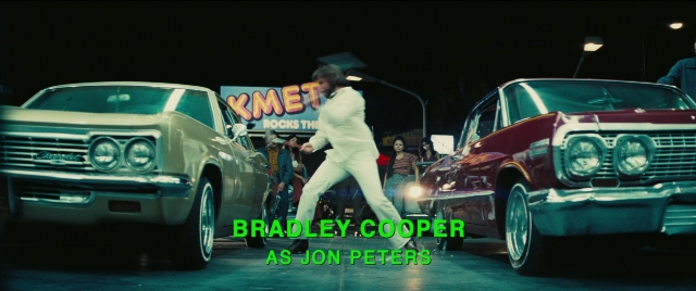 Wide shot frame from Licorice Pizza — street, car, suit