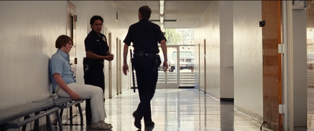 Wide shot frame from Licorice Pizza — sitting, walking, door