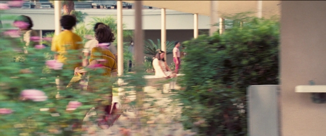Wide shot frame from Licorice Pizza — sitting, walking, dress