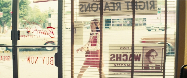 Wide shot frame from Licorice Pizza — walking, street, car
