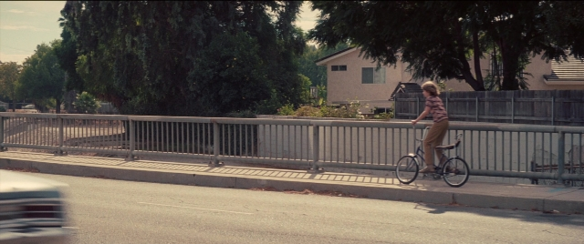 Frame from Licorice Pizza — street, car, bicycle