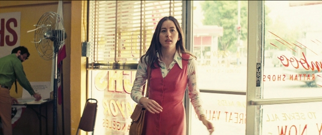 Medium shot frame from Licorice Pizza — standing, table, dress