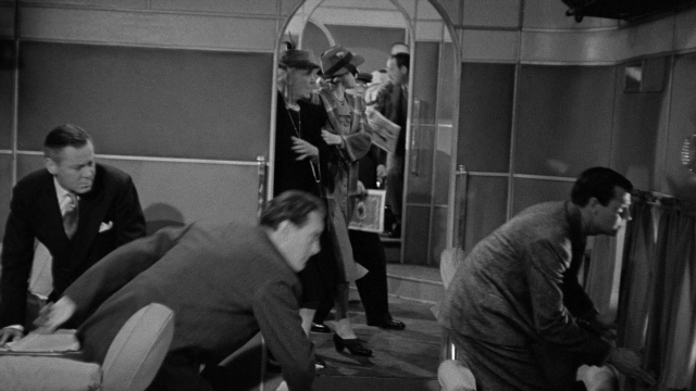 Wide shot frame from Foreign Correspondent — standing, door, mirror