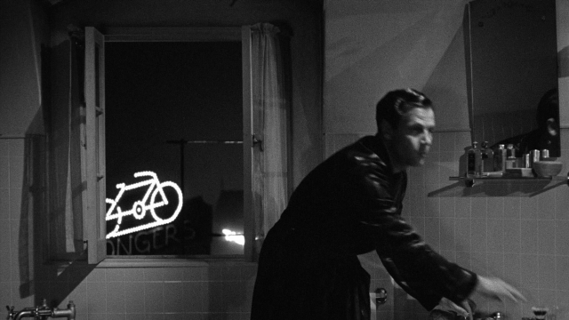 Wide shot frame from Foreign Correspondent — standing, mirror, coat