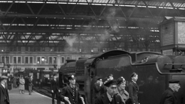 Wide shot frame from Foreign Correspondent — standing, hat, uniform
