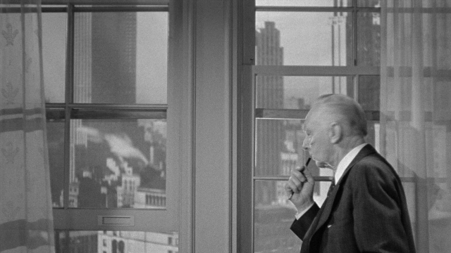 Medium shot frame from Foreign Correspondent — standing, hand, suit