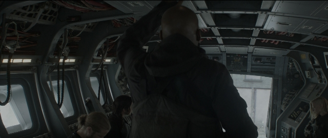 Wide shot frame from The Hunger Games: Mockingjay - Part 1 — sitting, standing, hat