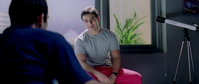 Wide shot frame from Zärtliche Begierde — sitting, room, dialogue