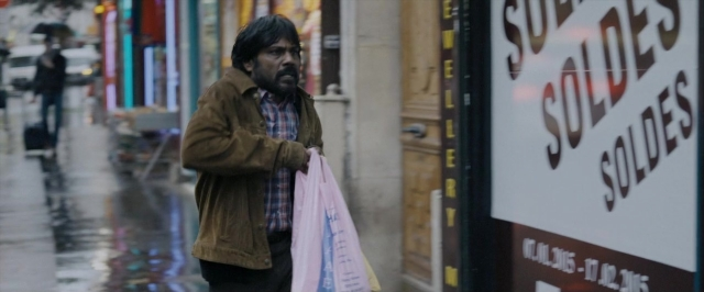 Wide shot frame from Dheepan — walking, street, car