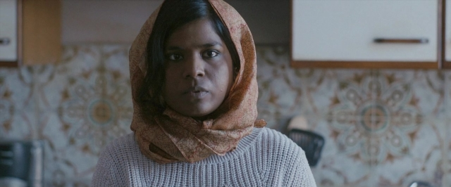 Medium shot frame from Dheepan — standing, kitchen, face