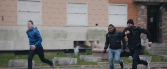 Wide shot frame from Dheepan — street, jacket, person