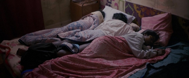 Frame from Dheepan — room, bed, shirt