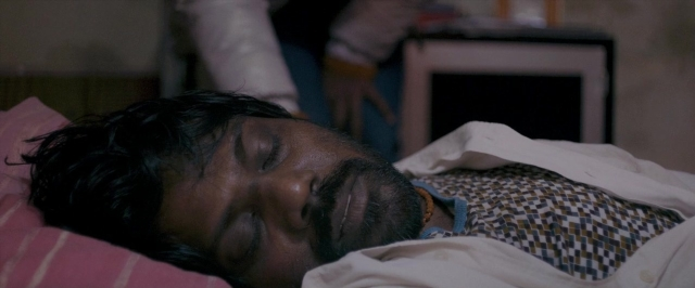 Wide shot frame from Dheepan — room, bed, hand