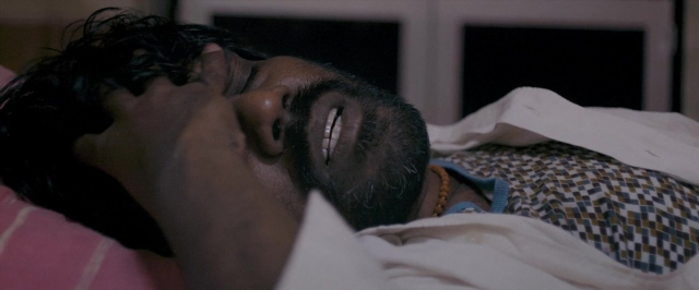 Wide shot frame from Dheepan — bed, shirt, bedroom