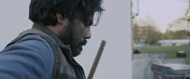 Wide shot frame from Dheepan — hand, beard, face