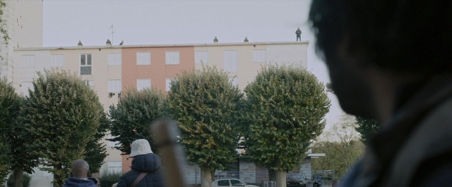 Frame from Dheepan — walking, street, hat