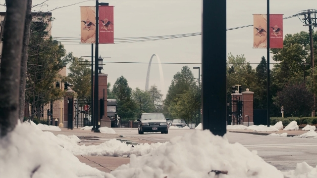 Wide shot frame from The Informant! — street, car, horse