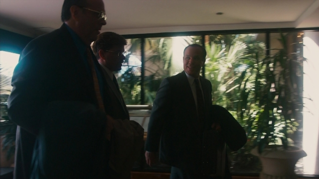Wide shot frame from The Informant! — standing, room, suit
