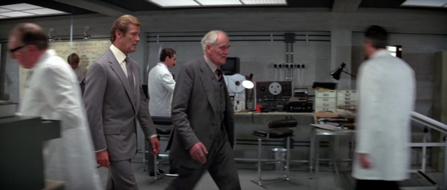 Wide shot frame from For Your Eyes Only — walking, room, coat
