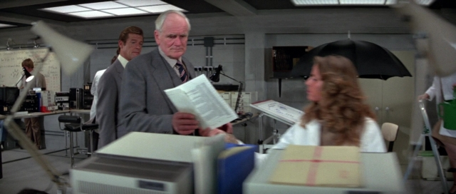 Wide shot frame from For Your Eyes Only — standing, room, coat