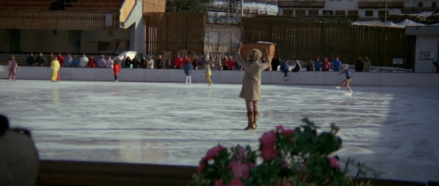 Wide shot frame from For Your Eyes Only — standing, coat, flower