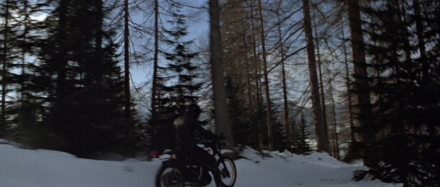 Wide shot frame from For Your Eyes Only — hat, bicycle, smoke
