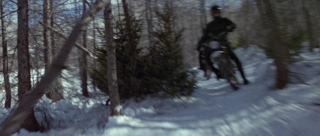 Wide shot frame from For Your Eyes Only — hat, bicycle, forest
