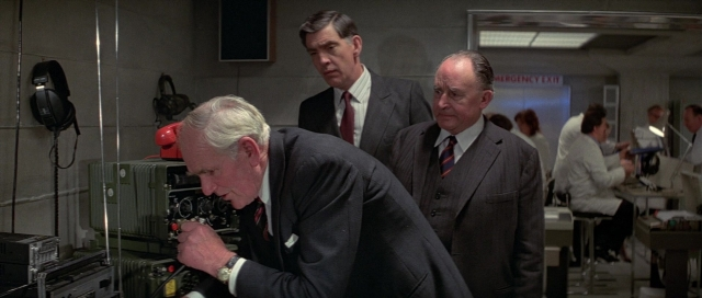 Wide shot frame from For Your Eyes Only — room, phone, suit