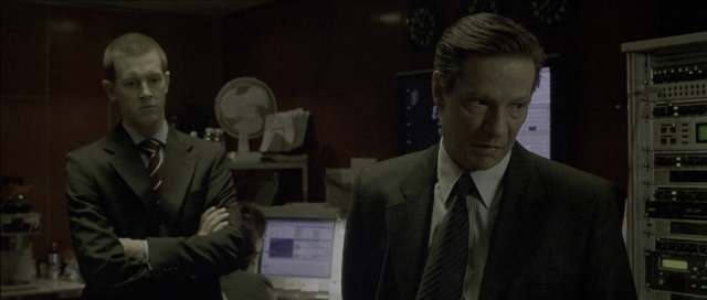 Wide shot frame from The Bourne Identity — standing, room, suit