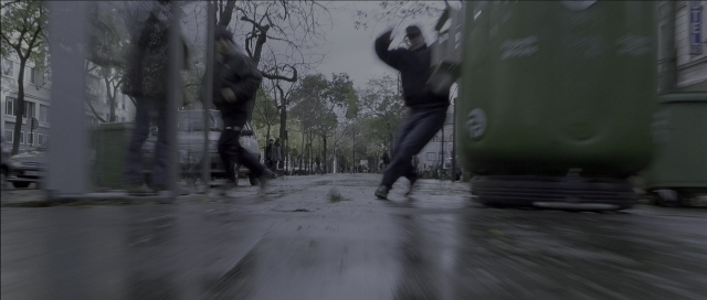 Wide shot frame from The Bourne Identity — walking, street, bag
