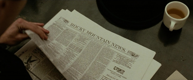 Wide shot frame from The Assassination of Jesse James by the Coward Robert Ford — sitting, table, hand