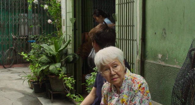 Frame from Lahn Mah — sitting, shirt, face