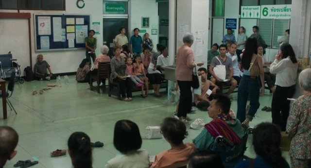 Medium shot frame from Lahn Mah — sitting, standing, room