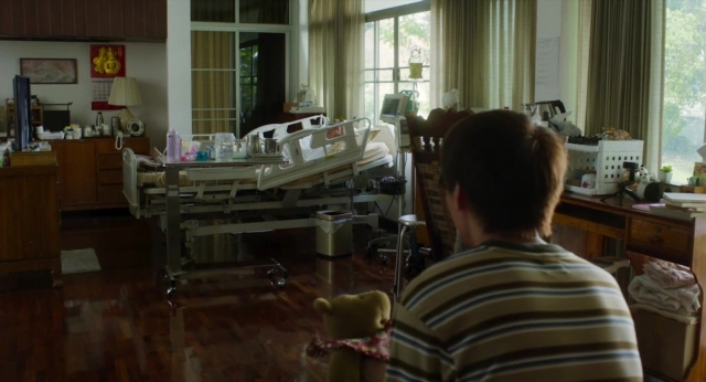 Wide shot frame from Lahn Mah — sitting, book, bed