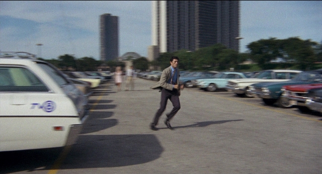 Wide shot frame from Medium Cool — walking, car, suit