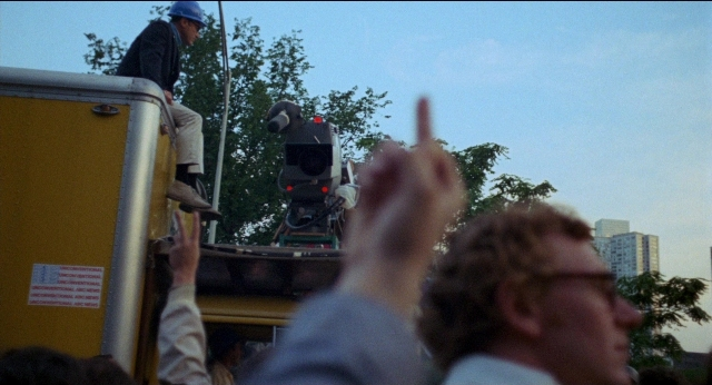 Frame from Medium Cool — standing, hat, person