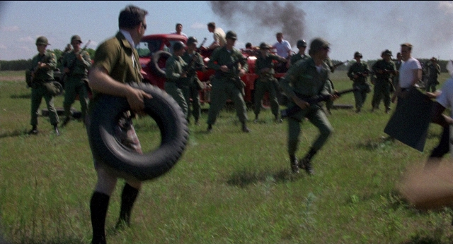 Wide shot frame from Medium Cool — walking, car, smoke