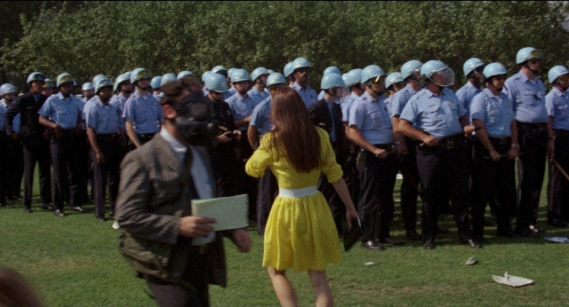 Wide shot frame from Medium Cool — standing, walking, suit