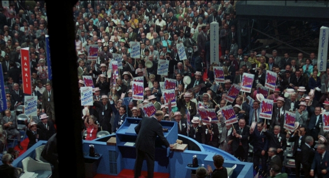 Wide shot frame from Medium Cool — sitting, standing, dialogue