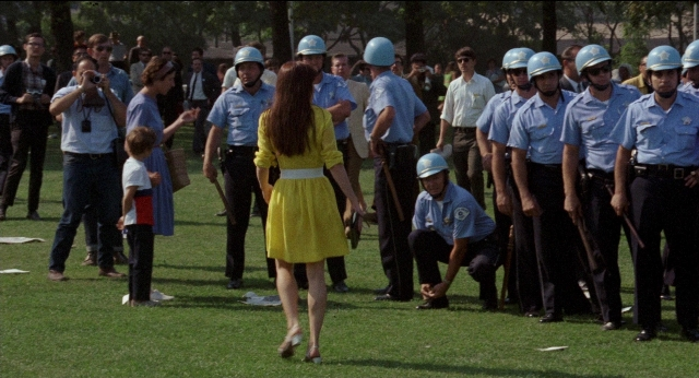 Wide shot frame from Medium Cool — standing, walking, dress
